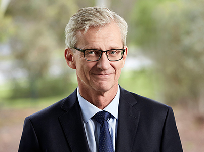 Dr Carl-Magnus Larsson looking thoughtfully at the camera in a business suit over a blurred backdrop.