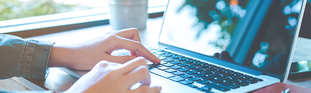 Cropped and zoomed shot fingers typing on a laptop keyboard