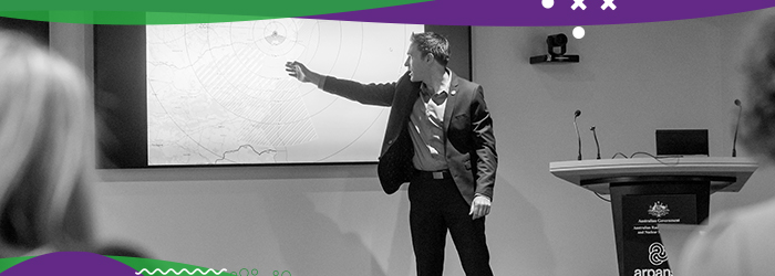 Man in business attire pointing at map on large screen