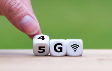 human fingers turning a 4G cube into a 5G cube - the cube has writing '4G' and the writing is being moved to say '5G'