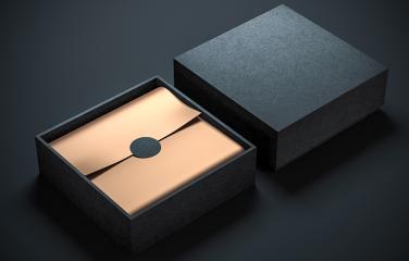 Open gift box with sealed golden envelope inside