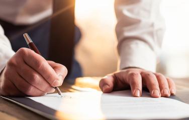 close up of document being signed with an elegant pen, body of person cropped out of shot
