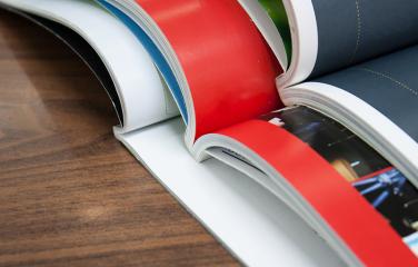 Three open books stacked on top of one another on a wooden table.