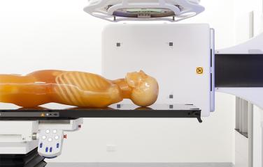 Dummy without arms laying flat on a table surrounded by medical equipment