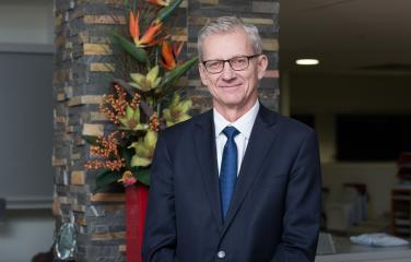 Dr Carl-Magnus Larsson standing with glasses and a suit near flowers