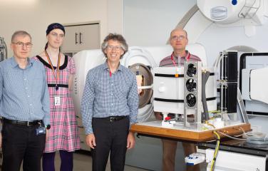 Scientists standing in front of a linac accelerator and water calorimeter