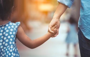 A mother and daughter hold hands as they walk down the street