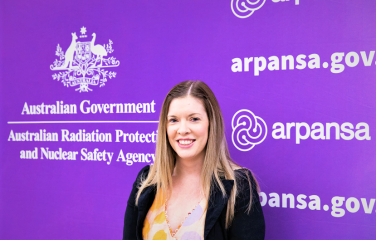 Headshot of Associate Prof Sarah Loughran in front of an ARPANSA banner