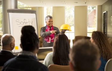A woman gives a safety lecture to a group of employees