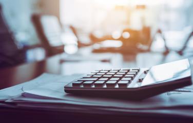 A calculator sitting on a stack of papers in an board room setting
