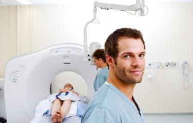 Patient undergoing medical scan tended by male and female doctors