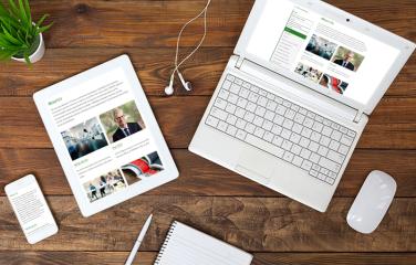 A mobile, tablet and laptop on a wooden desk all showing the ARPANSA About Us page in responsive designs.