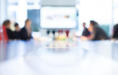 A blurred, expanded view of several people having a meeting around a table.