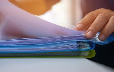 close up of hand filtering through pages of documents in folders
