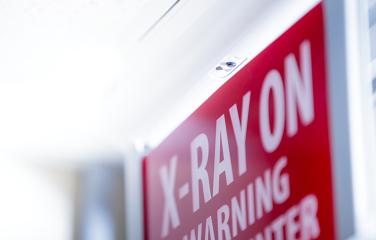 An angled and slightly out of focus red sign that reads "X-ray on, warning, do not enter" with some of the words slightly out of view in the picture.