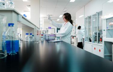 Female scientist in a laboratory with bottles and other scientific equipment.
