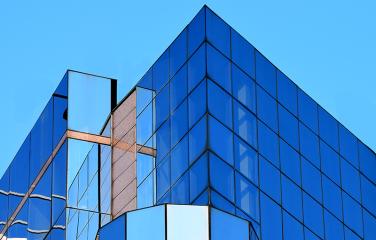 Several tall buildings of various heights and shapes with reflective window panels cascading around all of the walls