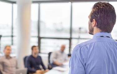 Man standing and delivering a presentation to seated learners.