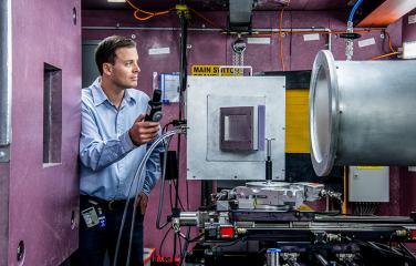 Man conducting testing within a room full of machinery and wires.