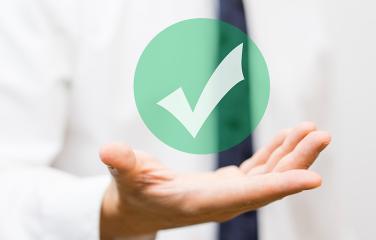 Close-up of business man’s hand holding a virtual green tick.
