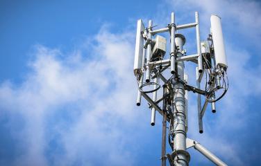 Top of a mobile phone base stations with a cloudy sky background.