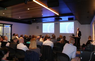 Hilaire Mansoux speaking to a crowded room