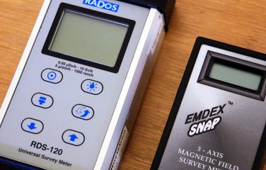 Close-up of two different meters laying side by side on a wooden table.