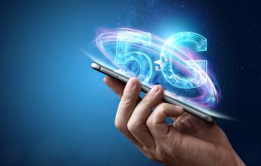 close up of a hand holding a mobile phone with '5G' extruding from the phone