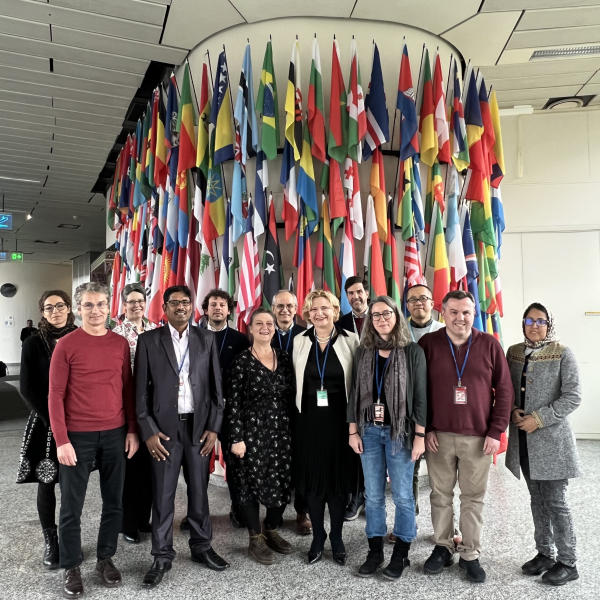 A group of people are posing in front of world flags at the united nations