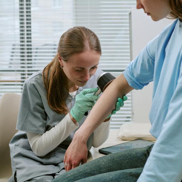 Adult Woman Dermatologist Examining Woman Arm in Clinic