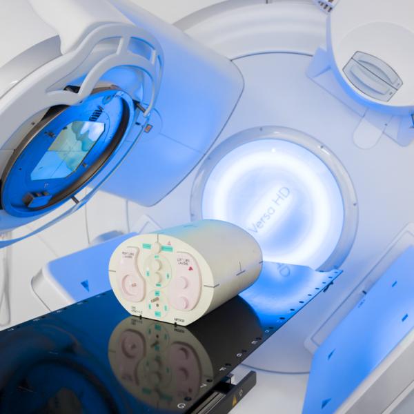A medical linear accelerator (LINAC) radiotherapy machine with a cylindrical dosimetry phantom positioned on the treatment couch. 