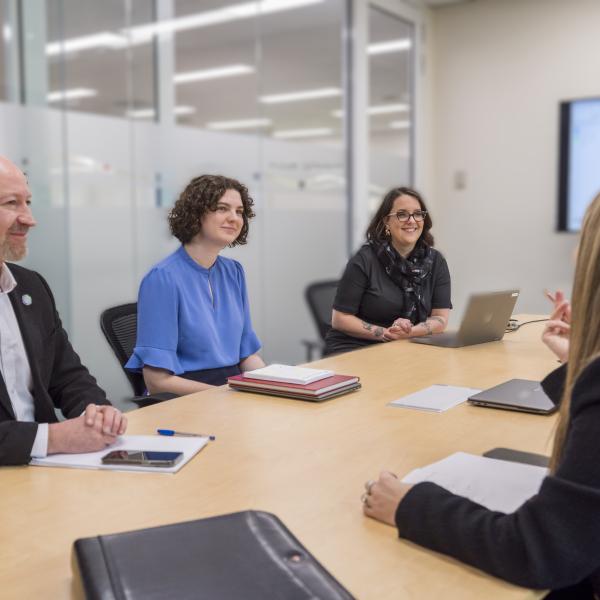 People are gathered around an office table having a meeting
