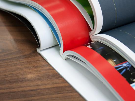 Three open books stacked on top of one another on a wooden table.