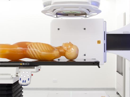 Dummy without arms laying flat on a table surrounded by medical equipment
