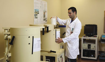 ARPANSA radiochemist placing a food sample into the Germanium Gamma Ray spectrometer to measure radioactivity.