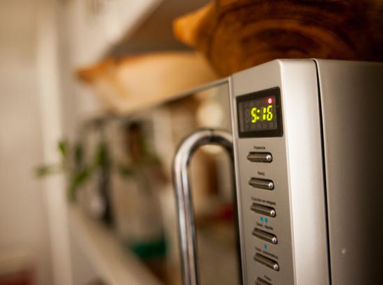 Close-up of microwave focusing on buttons and timer which reads 5:16.