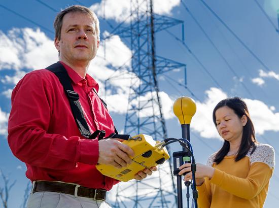 Casually dressed male and female scientists performing measurements in a field.