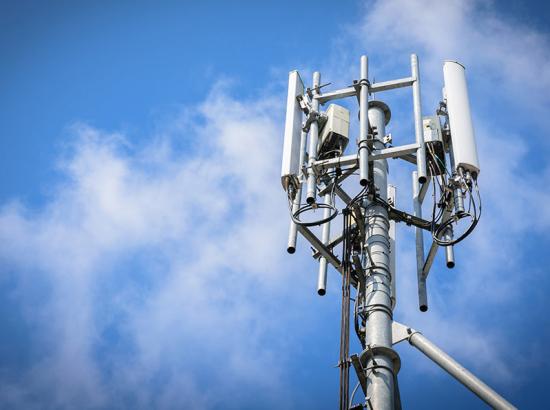 Top of a mobile phone base stations with a cloudy sky background.