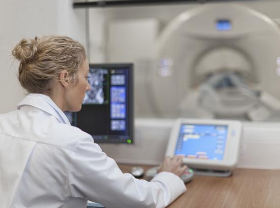 A doctor operating a CT scanner in a hospital.